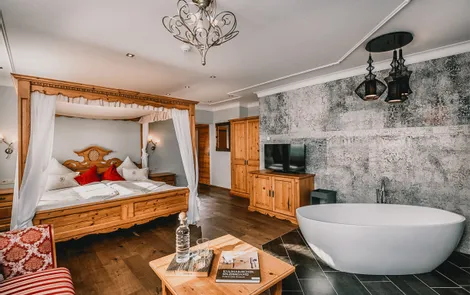 Alpenglühen Luxuriöses Hotelzimmer mit Himmelbett, freistehender Badewanne, Holzmöbeln und modernem Dekor